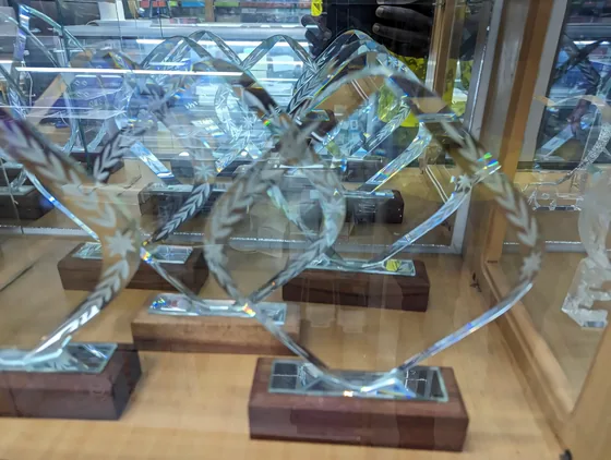 Clear acrylic awards on wooden bases in a display cabinet.