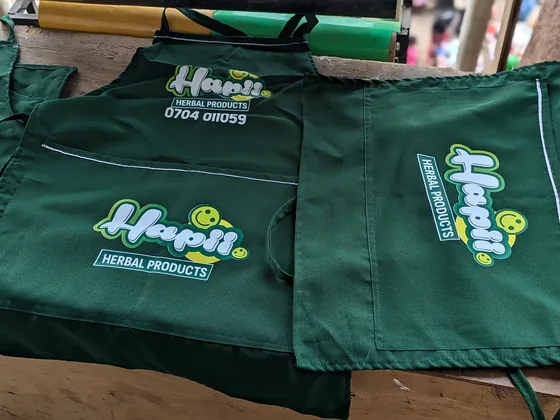 Green aprons printed with the Hapii Herbal Products logo.