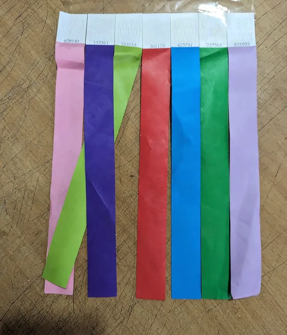 A row of event wristbands in pink, purple, green, red, blue and lilac.