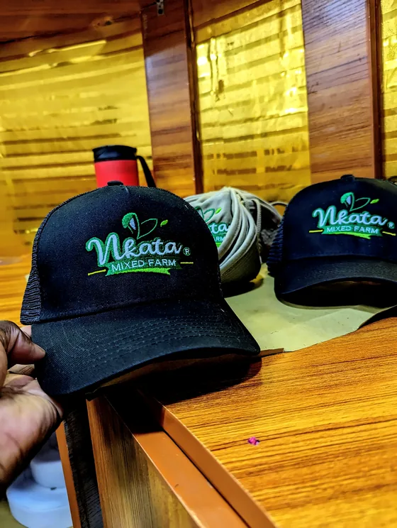Black trucker caps embroidered with the green Nkata Mixed Farm logo.