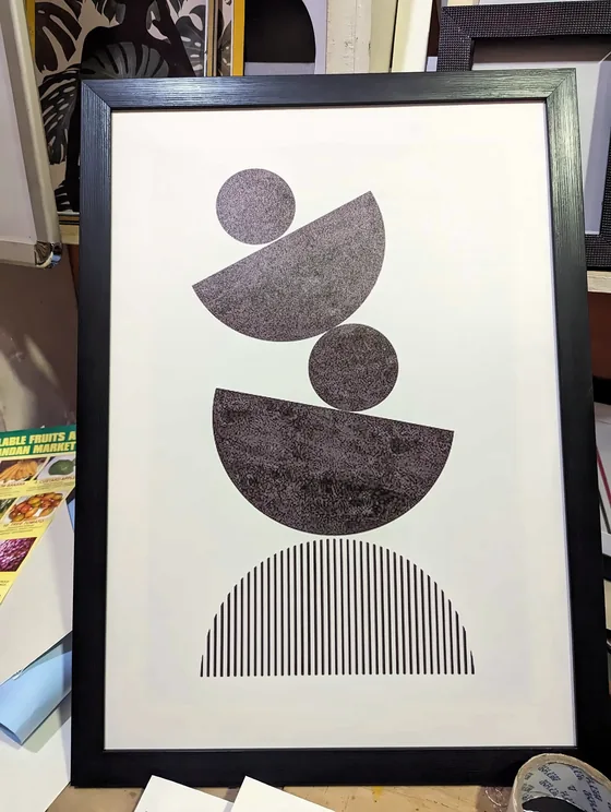 Framed print of stacked black and grey half-circles on white.