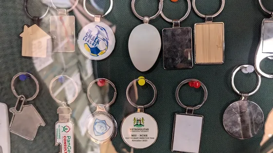 Metal and printed keyrings in several shapes laid out on a dark cloth.