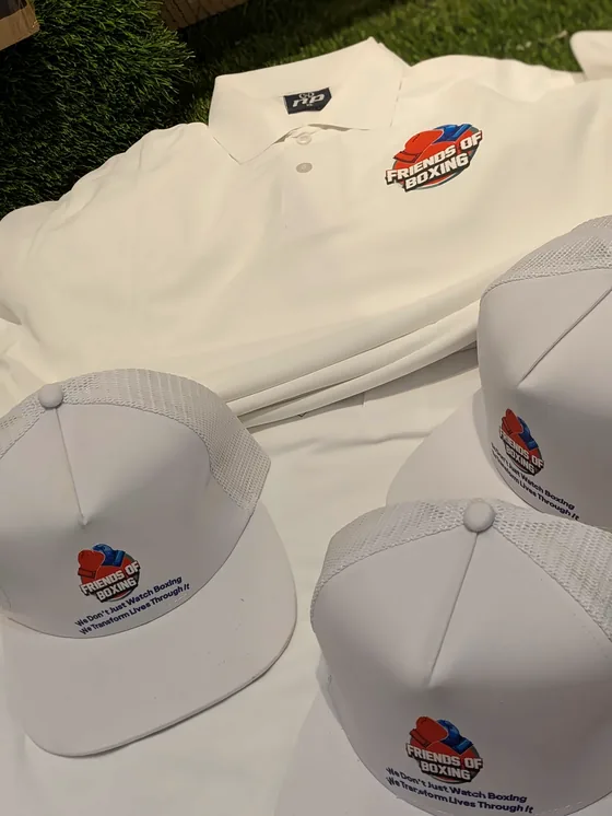 White polo shirt and white caps with a Friends of Boxing logo.